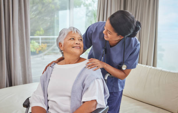 latynoska seniorka na wózku inwalidzkim i jej pielęgniarka w domu starców. młoda pielęgniarka mieszanej rasy i jej pacjent w salonie - senior lifestyle zdjęcia i obrazy z banku zdjęć