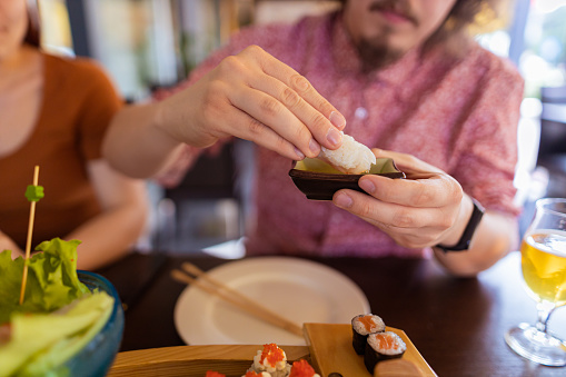 Cut out photography of a hand of a man with shrimp putting in soy sauce