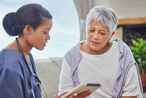 istock A hispanic senior woman in on a cosy sofa and her female nurse in the old age home and using a digital tablet. Mixed race young nurse and her patient talking in the lounge 1404182675