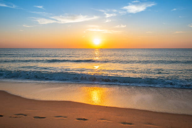 Beautiful sunset on the beach. Summer travel vacation concept with tropical beach and beautiful colorful sunset with sun just above the horizon on an idyllic beach in Ft Lauderdale, Florida. footprints in the sand poster stock pictures, royalty-free photos & images