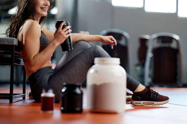A fit, slim sportswoman is drinking protein drink she made while taking a break from workout. stock photo