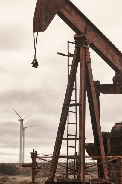 istock Oil pumping machine and windmills. Petroleum extraction. Global warming 1404189375