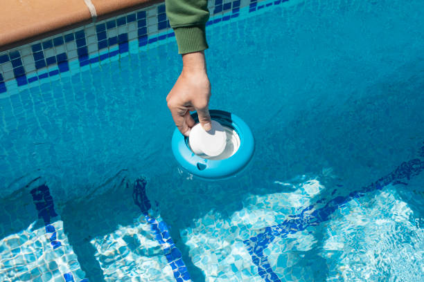 istock Operator inserting a chlorine tablet into a floating pool dispenser to level the ph.Chlorine and floating dispenser for summer pool maintenance.Copy space 1404190439