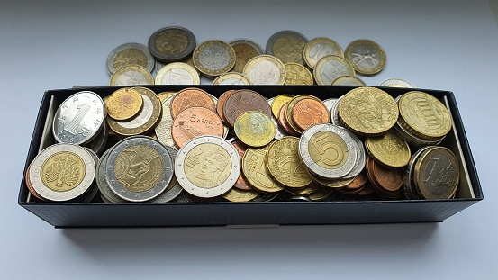 Coins from different countries of the world in a black box. Savings for a rainy day. Euro, Polish zloty, Chinese yuan, Egyptian pounds