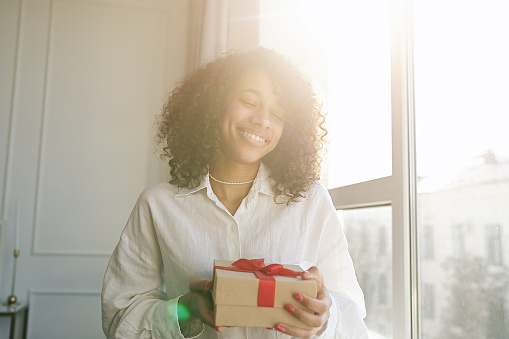 Excited african American young woman unpack gift box, overjoyed girl feel euphoric open shipped