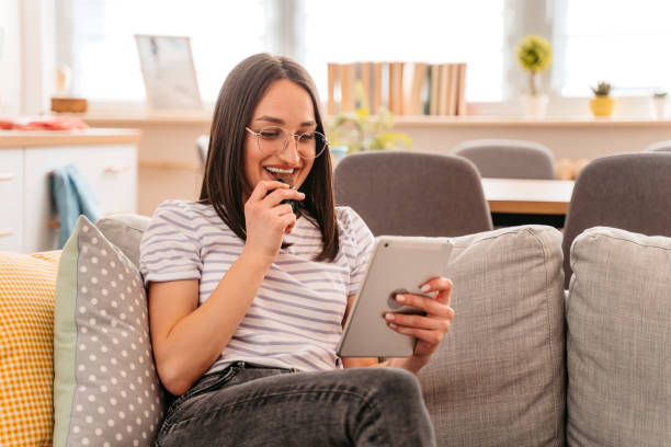 Young Woman Eating A Chocolate Bar And Using Tablet