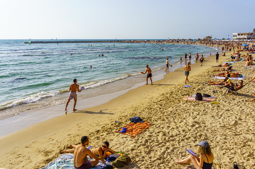 Tel-Aviv, Israel - June 17, 2022: Beach scene with visitors in various activities, in Tel-Aviv, Israel