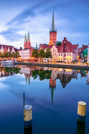 Cityscape image of riverside Lubeck  with reflection of the city in Trave River at sunset.