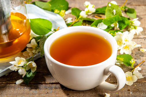 Herbal jasmin flower tea. Jasmine green tea in  glass teapot and white tea cup, with fresh jasmin blossom