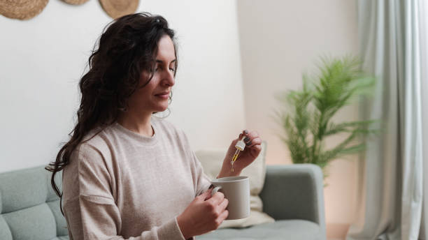 woman taking cbd oil for anxiety treatment - vitamins and supplements - druppelfles stockfoto's en -beelden