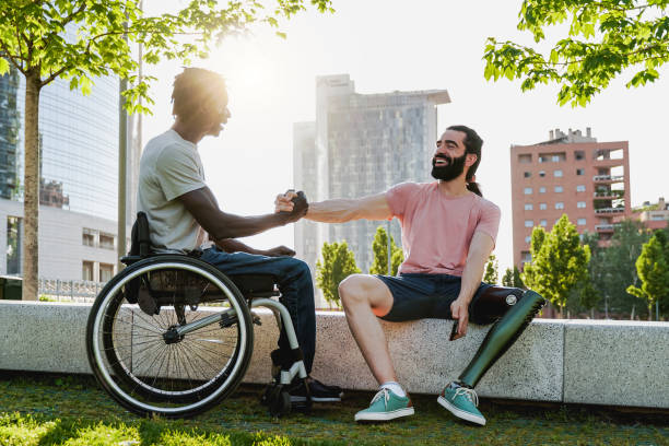 les personnes handicapées multiethniques se saluent à l’extérieur - focus sur l’homme droit avec une prothèse de jambe - sports en fauteuil roulant photos et images de collection