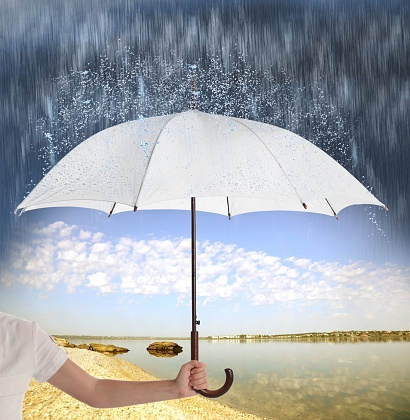 Woman with open umbrella under heavy rain near river, closeup
