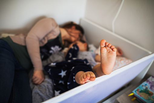 Baby's foot in bed while lying with mother