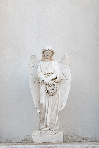 white stone angel holding wreath