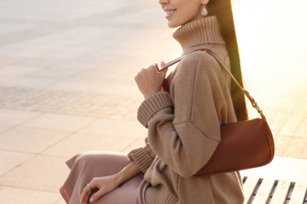 mujer joven de moda con bolso elegante en el banco al aire libre, primer plano - skirt brown fotografías e imágenes de stock