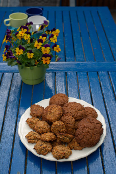 쿠키와 노란색 꽃이 파란색 테이블에 있습니다. 스톡 사진