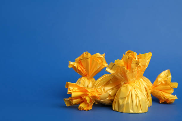 istock Candies in yellow wrappers on blue background. Space for text 1404206291
