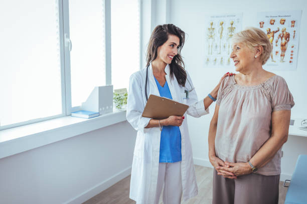Shot of a senior woman having a consultation with her doctor. Shot of a senior woman having a consultation with her doctor. Senior woman having a doctors appointment. Doctor in blue uniform and protective face mask giving advice to Senior female patient at hospital old woman smiling tablet stock pictures, royalty-free photos & images