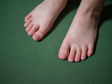Child stand barefoot on the green mat