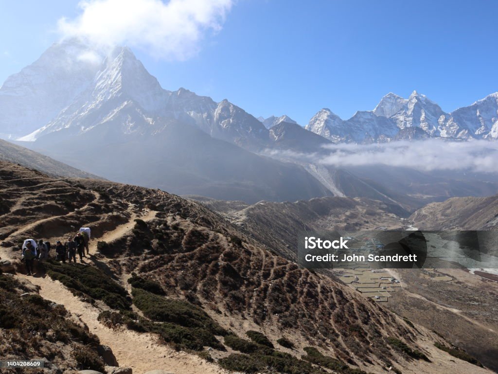 Trekking away from Dingboche Trekking away from Dingboche in Nepal. The village of Pheriche is seen in the distance on the right with the rugged mountain, Ama Dablam, on the left. Adventure Stock Photo