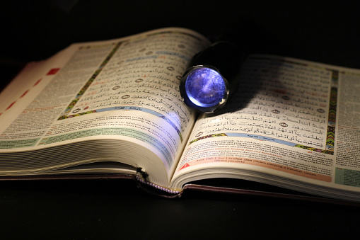 Quran close up in the dark room with low light and light from flashlight