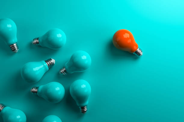 istock Orange lamp stands out from other lamps on a turquoise background. 1404209882