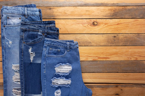 istock Torn jeans denim at wooden background texture. Blue Jeans fabric on tabletop 1404212227