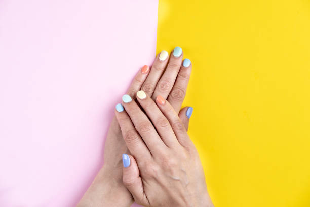 istock Pastel manicure hands close up on pink an yellow background. 1404213858