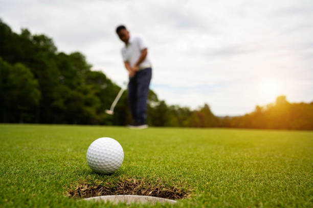 그린 골프에 공을 올려 놓는 골퍼, 태양에 렌즈 플레어 저녁 시간. - golf ball leisure activity sport nature 뉴스 사진 이미지