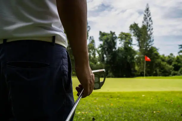 man white shirt blue pants In his hand, the putter prepares for the next golf shot. Sports that people around the world play during quarantine for health.