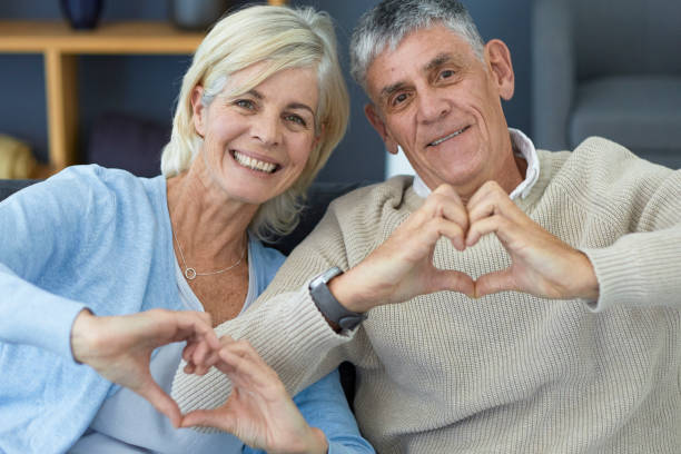 istock Cute older couple making heart sign with their hands 1404217328