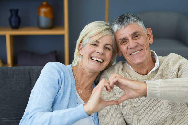 istock Cute older couple making heart sign with their hands 1404217405