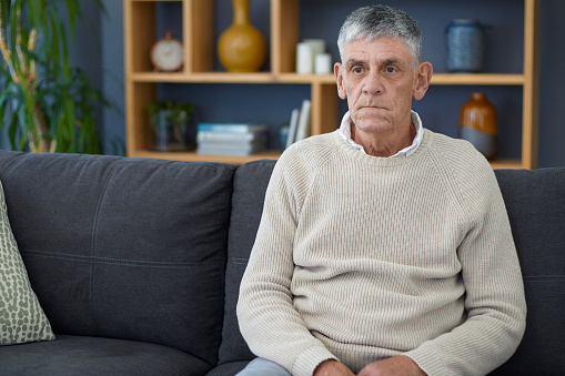 Worried senior man sitting alone in his home