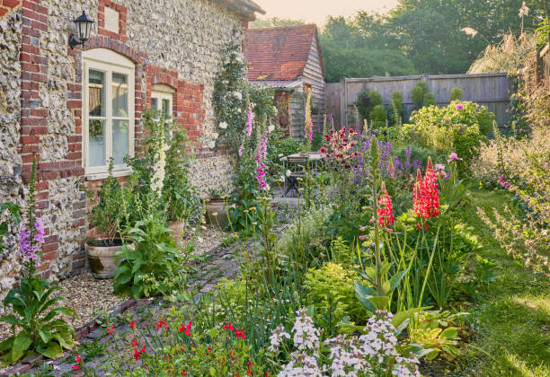 jardin de campagne anglais avec des plantes de jardin de chalet en été et un mur de silex - maison de campagne photos et images de collection