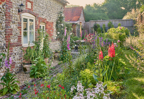 여름에는 코티지 정원 식물과 부싯돌 벽이있는 영어 국가 정원 - 시골집 뉴스 사진 이미지