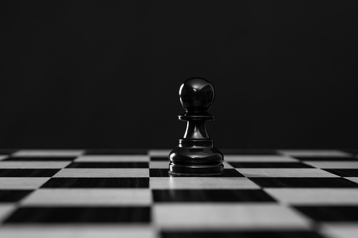 Black pawn chess piece on black background.