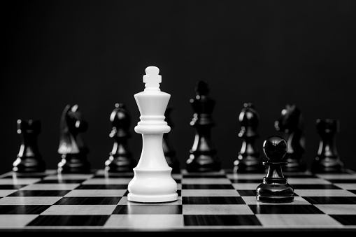 White chess king battle with black chess pieces.