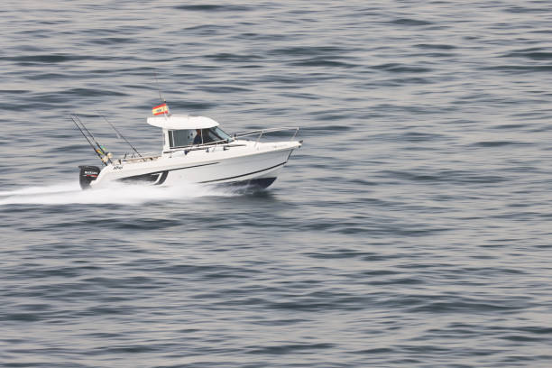 Small fast speed boat with 2 men at the helm zooming along at speed into the port of Gibraltar. stock photo