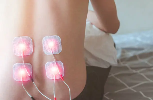 Selective focus on TENS Electrode Pads prepare for treatment on backpain, Electro stimulation machine in home, health problem and medical concept.