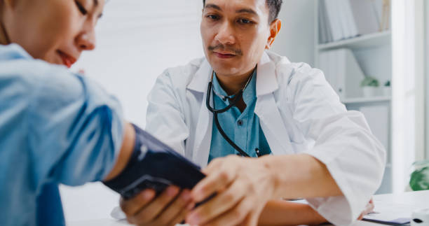 Close up of mature Asian man doctors measuring high low blood pressure of woman patient in health clinic. Close up of mature Asian man doctors measuring high low blood pressure of woman patient in health clinic. Medical health care concept. diabetes consultation stock pictures, royalty-free photos & images