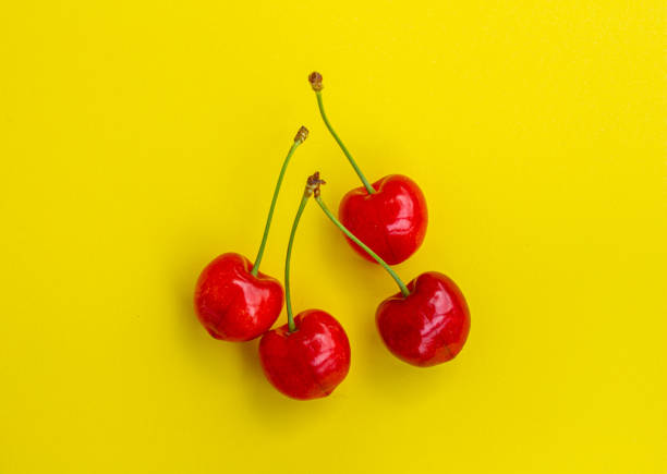 Top view cherry fruits isolated on yellow background. Minimal cherry background photo. Healthy summer fruits concept.