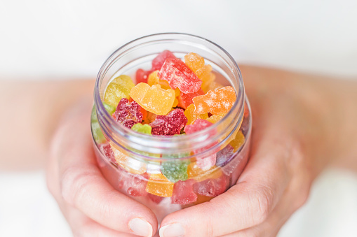 Female hands holding a glass jar of gummy bears close up. Childrens sweets. close up