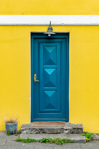 Blue door on a yellow painted colorful house, architecture detail in Reykjavik, Iceland