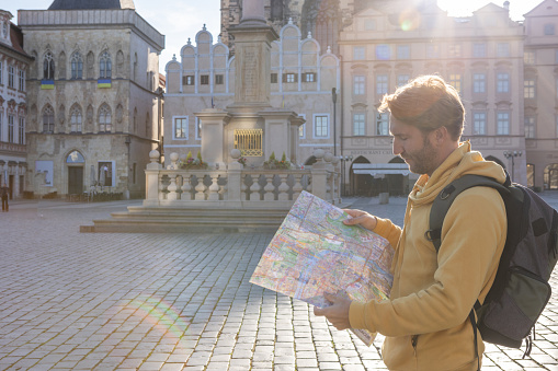 An unrecognisable female tourist holding and looking at the paper map to navigate the city streets