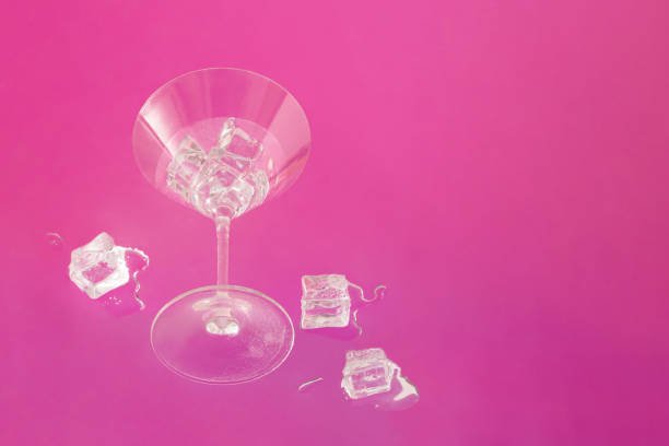 istock Trendy creative composition made of martini cocktail drinking glass with water or alcohol drink and melting ice cubes against vibrant pink background. Minimal summer party concept. 1404229728