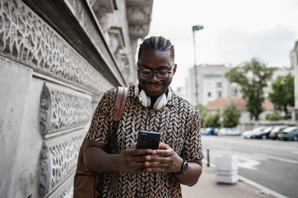 istock Young man smiling while walking in the city and using a phone 1404231194
