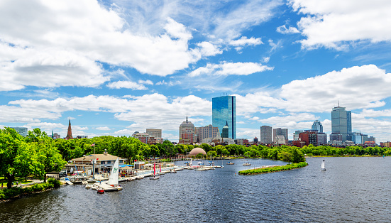 Boston, Massachusetts, USA - June 18, 2022:  Boston Back Bay skyline as seen from the Longfellow Bridge, across the Charles River and Esplanade. A community boating marina in the foreground. Also visible is the Hatch Memorial Shell on the Esplanade, the John Hancock Tower and the Prudential Center.