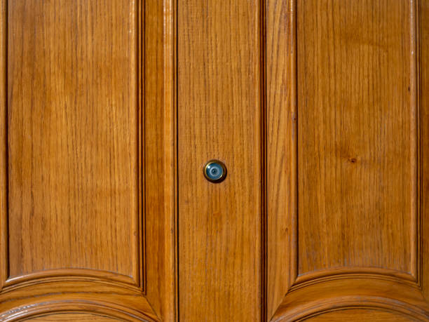 Door peephole on a wooden front door with a beautiful texture. A peephole in the center of a beautiful wooden vintage door with a light texture. peep hole stock pictures, royalty-free photos & images