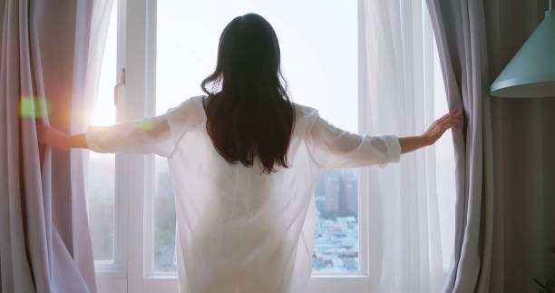 istock woman opens curtains in morning 1404233675