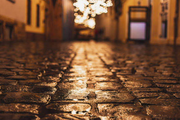 Wet cobblestone road with lights stock photo